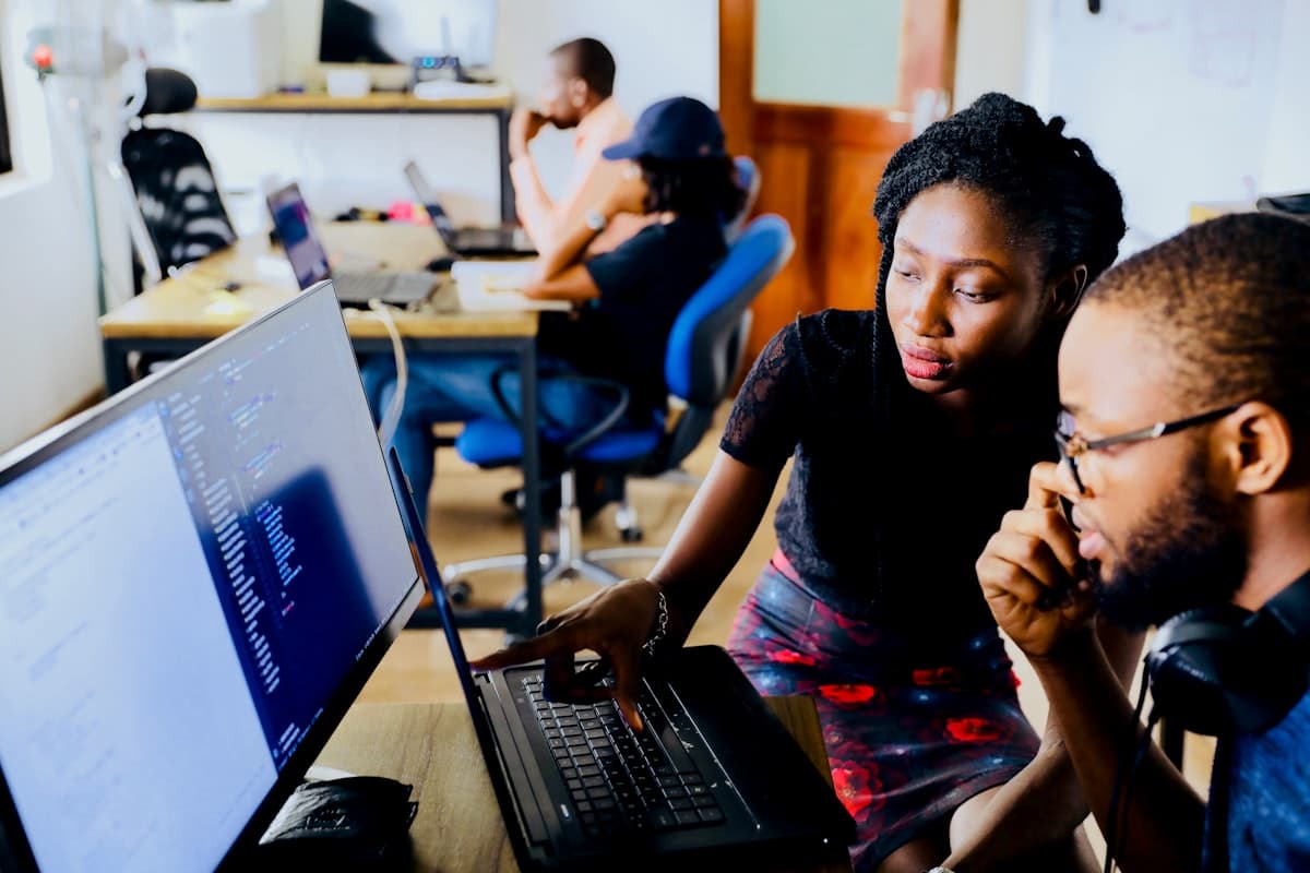 Two analysts reviewing data on a laptop and monitor together.
